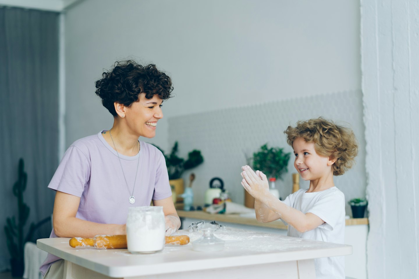 Woman and boy baking together in a sunny kitchen.