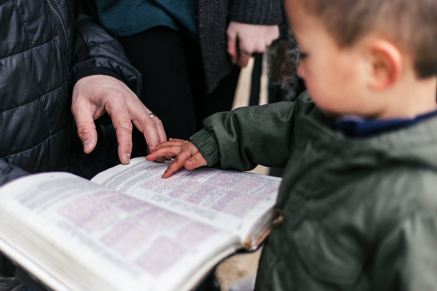 Adult and child pointing at words in an open book.