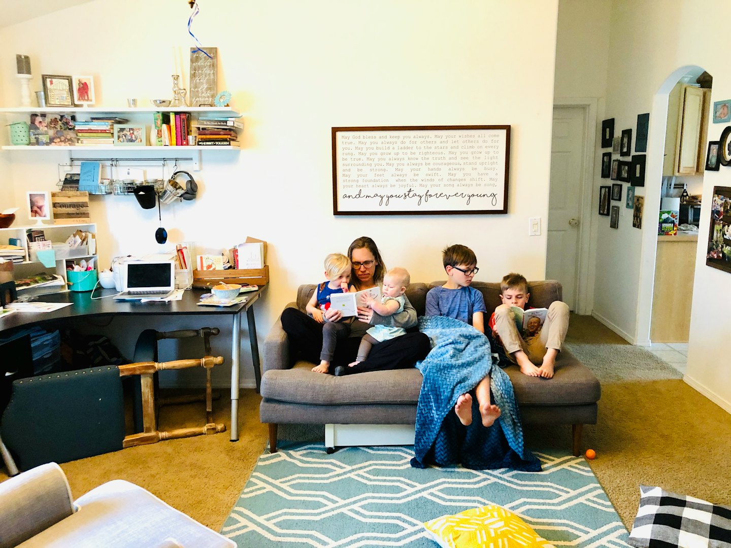 A mother reads a book to her child on a sofa.