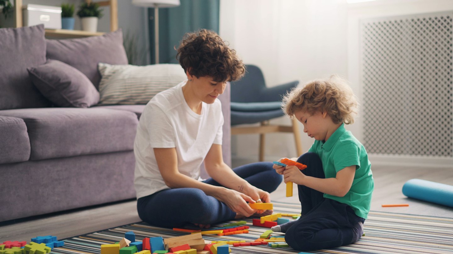 Mother and son playing with blocks on a striped rug.