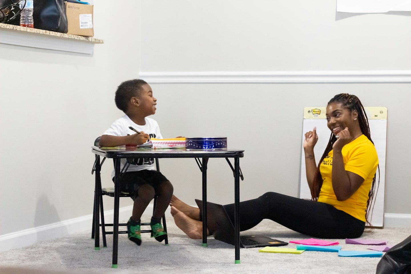 Woman and boy smiling during a tutoring session at a table.